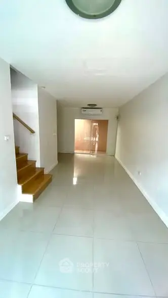 Spacious modern living room with sleek staircase and air conditioning, perfect for comfortable living.