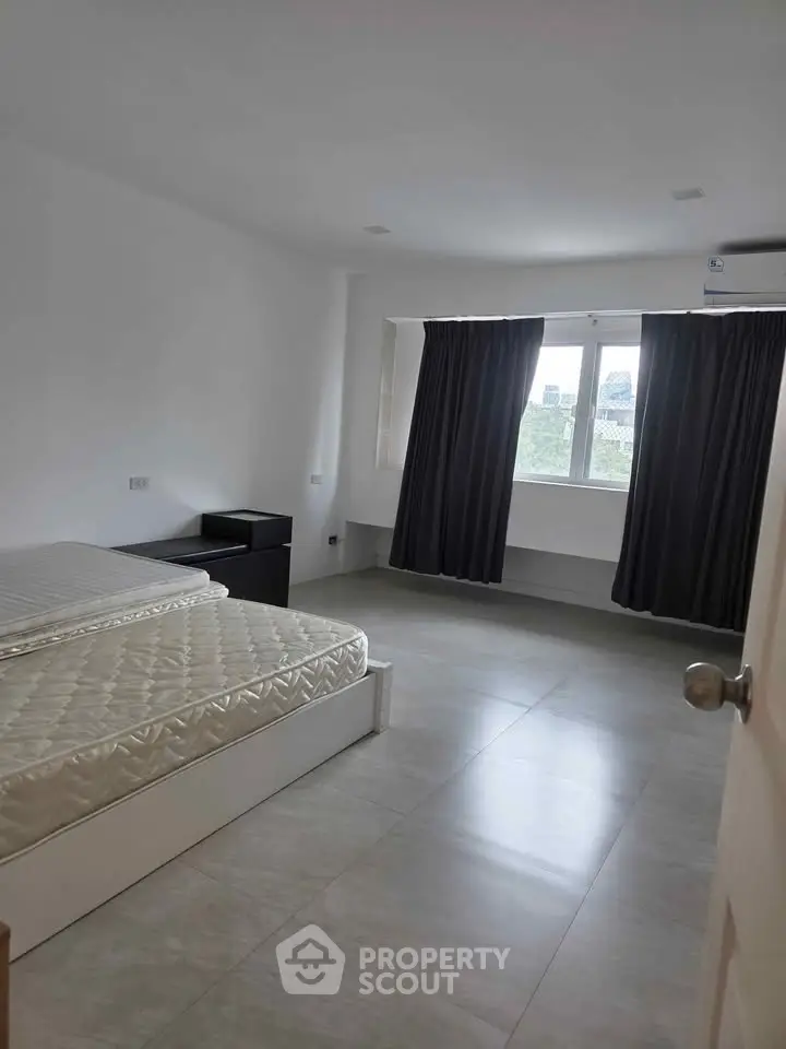 Spacious bedroom with large window and minimalist decor