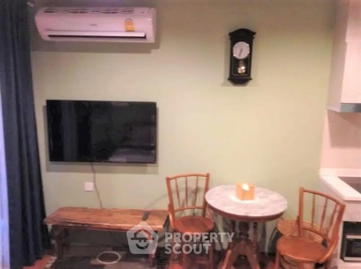 Cozy living area with wall-mounted TV and vintage clock, perfect for relaxation.