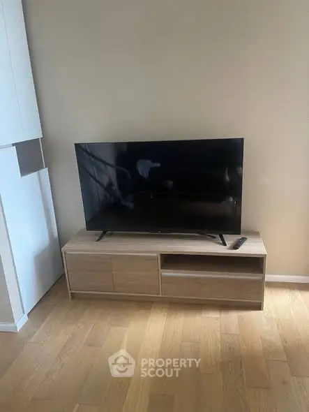 Modern living room with sleek TV stand and flat-screen TV on wooden flooring.