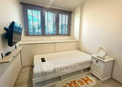 Cozy bedroom with single bed, wall-mounted TV, and large window with blinds.