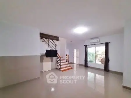 Spacious modern living room with staircase and large window view.