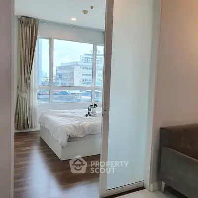 Modern bedroom with large windows and city view, featuring elegant curtains and wooden flooring.