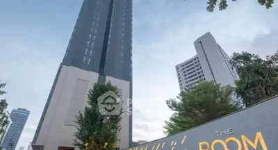 Modern high-rise building with sleek design and lush greenery in urban setting.