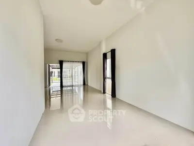 Spacious empty living room with glossy tiled floors and large windows for natural light.