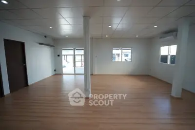 Spacious open-plan living area with wooden flooring and large windows