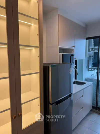 Modern kitchen with sleek cabinetry and stainless steel fridge in a compact layout.