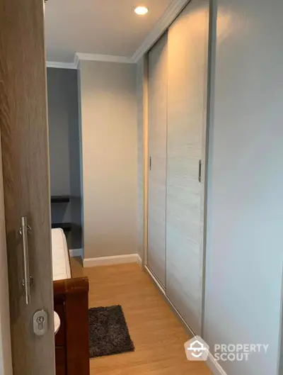 Cozy bedroom with large mirrored closet doors reflecting a well-lit space, featuring a plush rug and a glimpse into a study area.