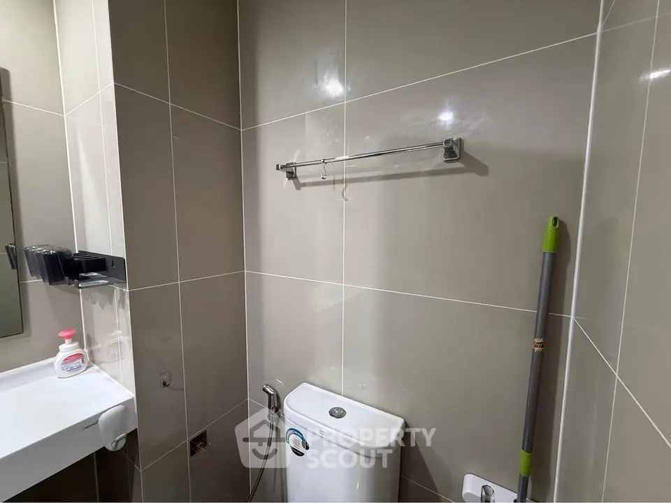 Compact bathroom with modern fixtures and tiled walls, featuring a toilet and sink.