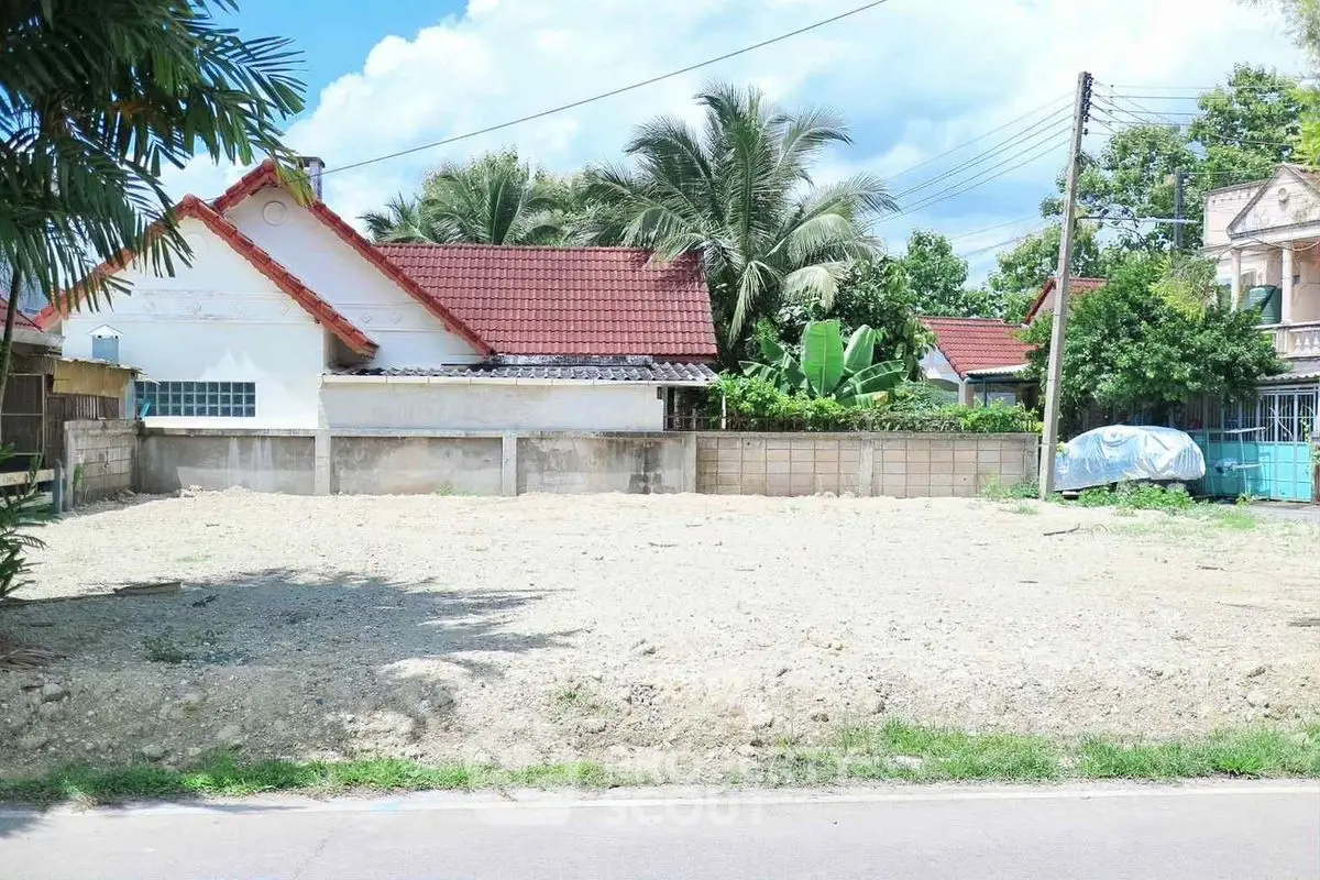Vacant land plot with potential for development in a residential area, surrounded by lush greenery and neighboring homes.