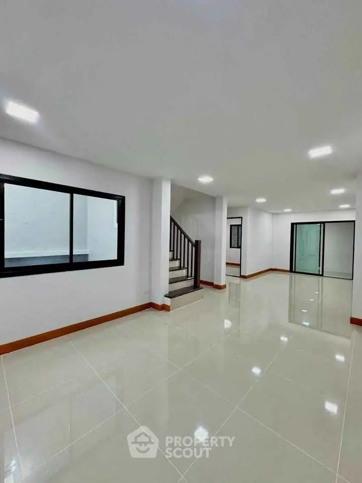 Spacious modern interior with glossy tiled floors and staircase, ideal for open layout living.