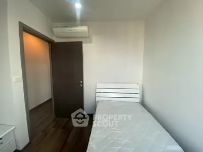 Cozy minimalist bedroom with single bed and air conditioning, perfect for a peaceful retreat.
