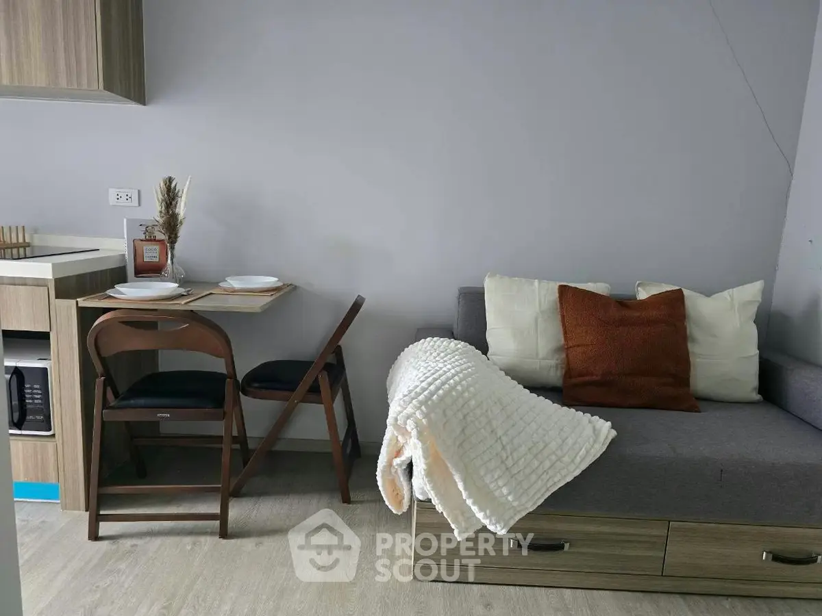 Cozy living room with modern furniture and dining area in compact apartment.