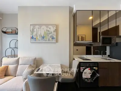 Modern living room with integrated kitchen and washing machine, featuring stylish decor and comfortable seating.