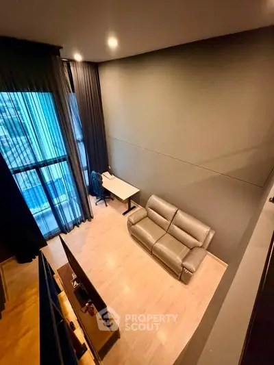 Modern loft-style living room with high ceilings and large windows, featuring a cozy sofa and a sleek desk.
