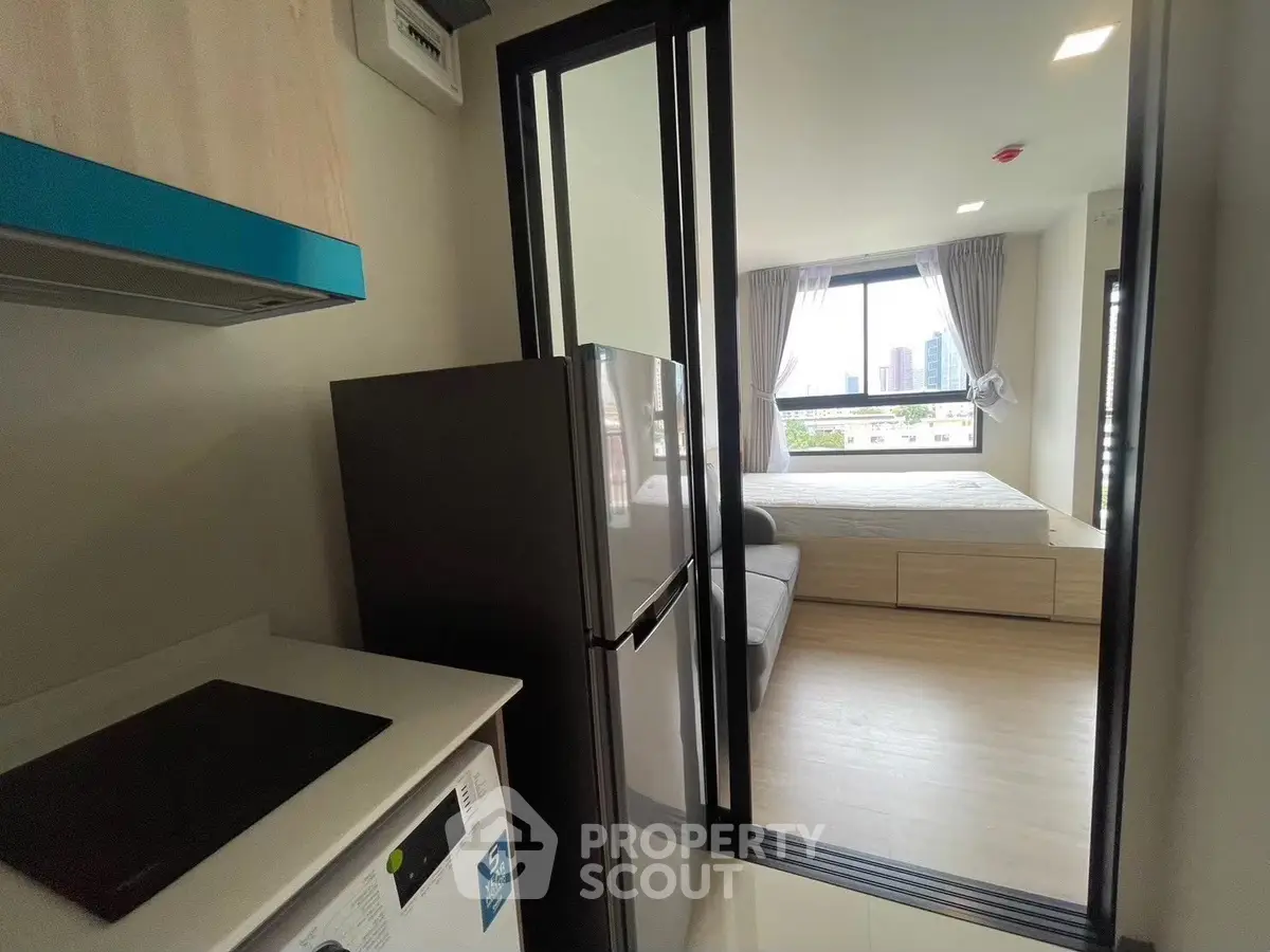 Modern apartment interior with compact kitchen and cozy bedroom view.