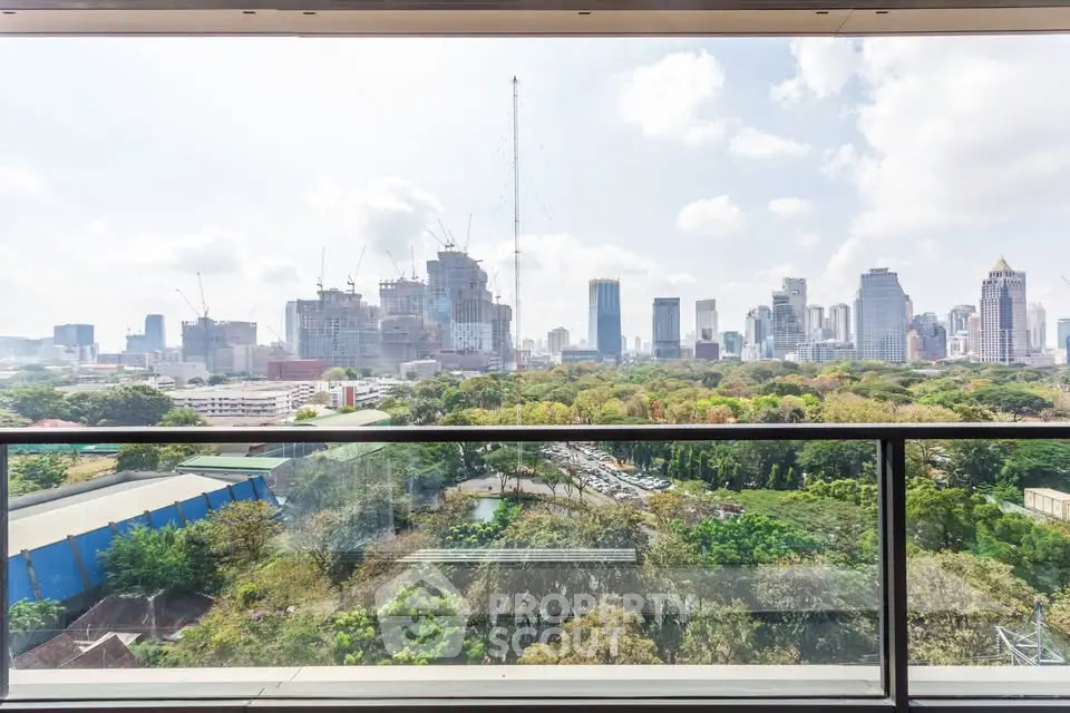Stunning cityscape view from a high-rise balcony overlooking lush greenery and urban skyline.