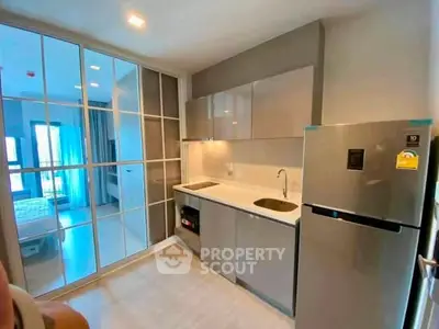Modern kitchen with sleek cabinetry and stainless steel fridge in a stylish apartment.