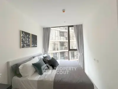 Modern bedroom with large window and stylish decor in a high-rise apartment.