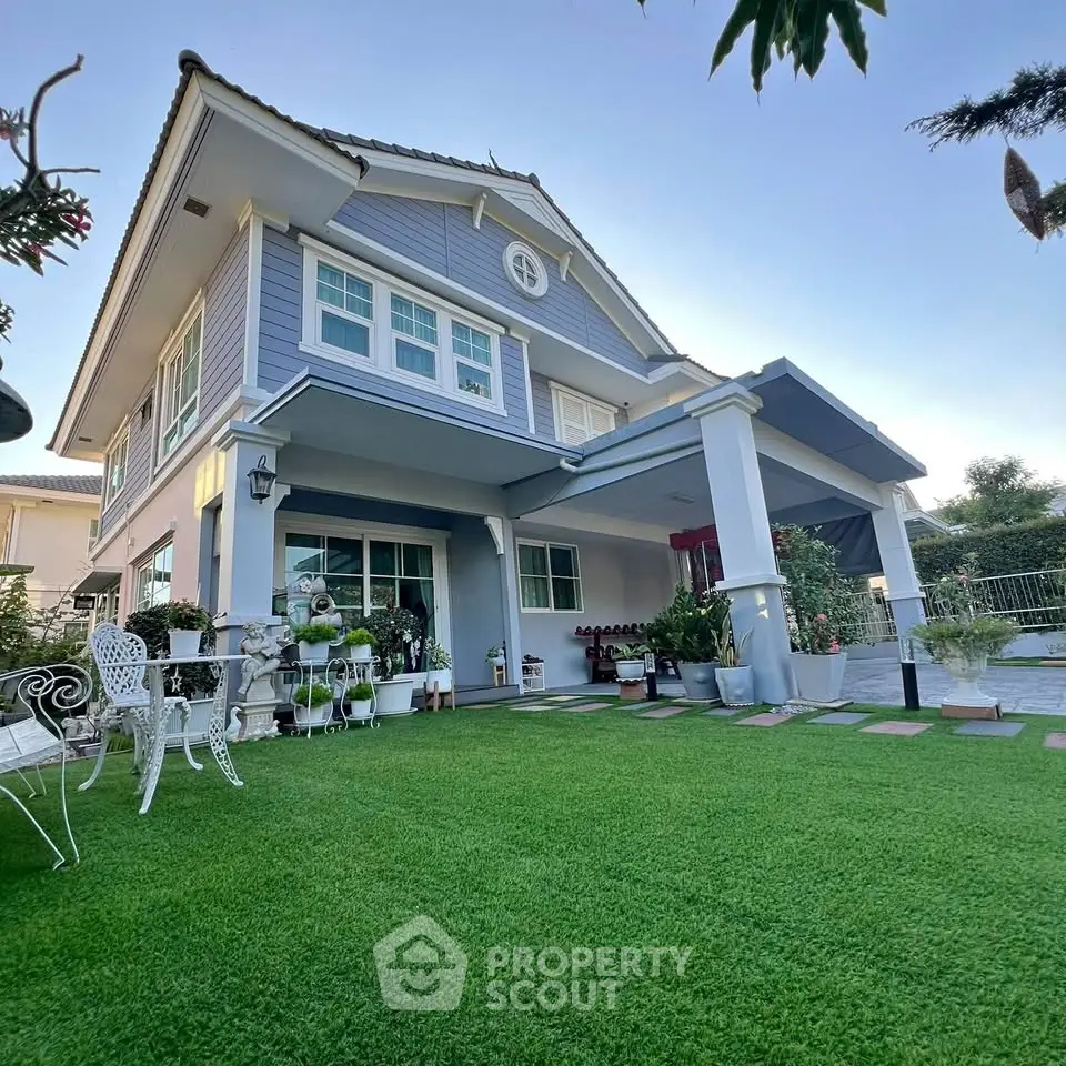Charming two-story house with lush garden and elegant outdoor seating area.