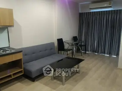Modern living room with sleek furniture and wooden flooring, featuring a cozy sofa and dining area.