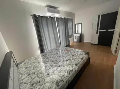 Spacious bedroom with modern decor and ample natural light, featuring a comfortable bed and stylish furnishings.