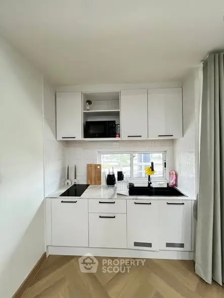 Modern compact kitchen with sleek white cabinets and built-in appliances