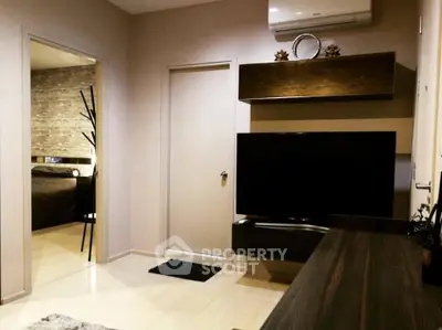 Modern living room with sleek TV setup and stylish decor, leading to a cozy bedroom.