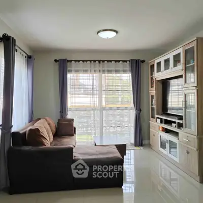 Spacious living room with modern entertainment center and large windows.