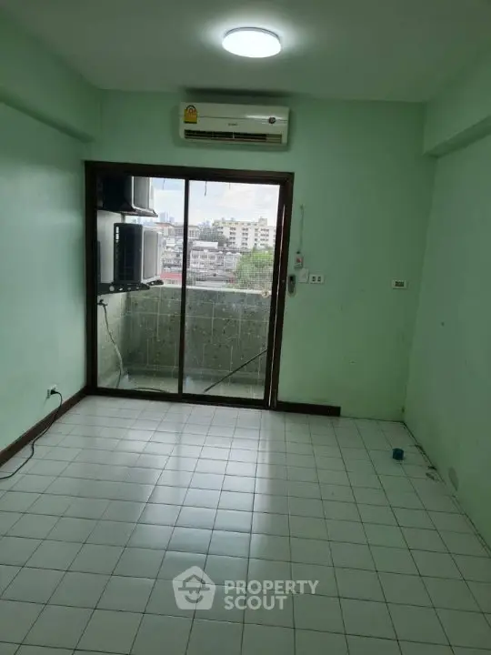 Spacious living room with balcony and city view, featuring air conditioning and tiled flooring.