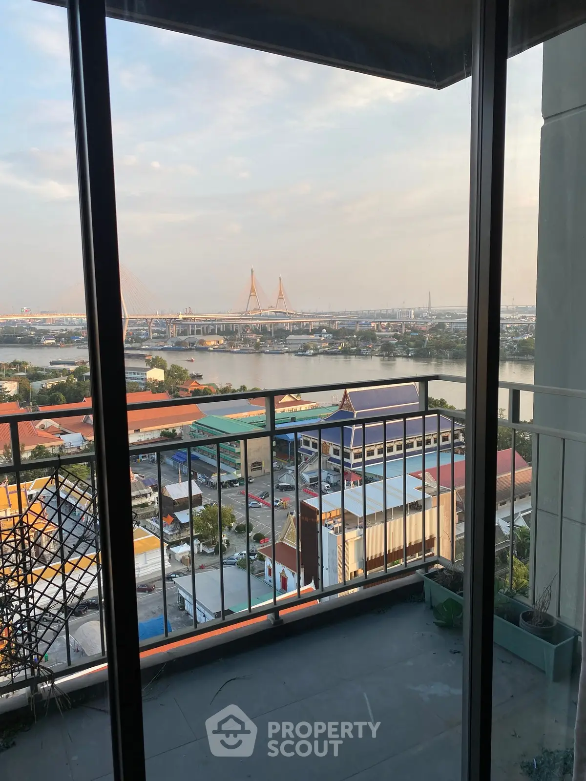 Stunning high-rise balcony view overlooking river and cityscape with iconic bridge.
