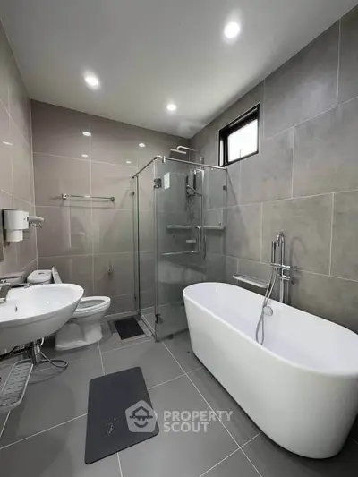 Modern bathroom with sleek design featuring bathtub and glass shower enclosure.