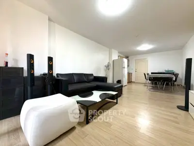 Spacious modern living room with sleek black furniture and open dining area