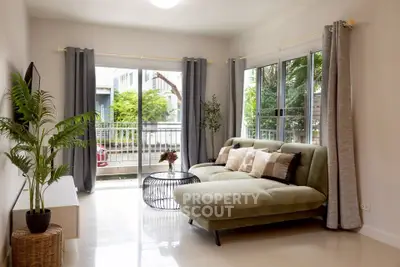 Modern living room with large windows and stylish furniture, offering a bright and inviting atmosphere.