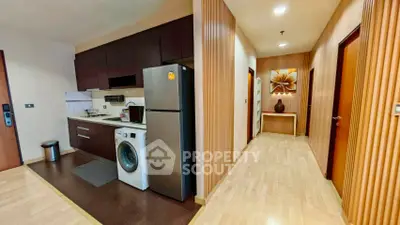 Modern apartment interior with kitchen and hallway featuring wooden accents and sleek appliances.