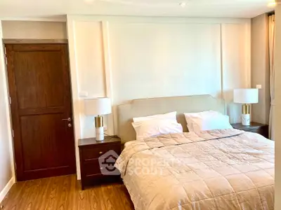 Elegant bedroom with cozy bed, wooden flooring, and stylish bedside lamps in a modern apartment.