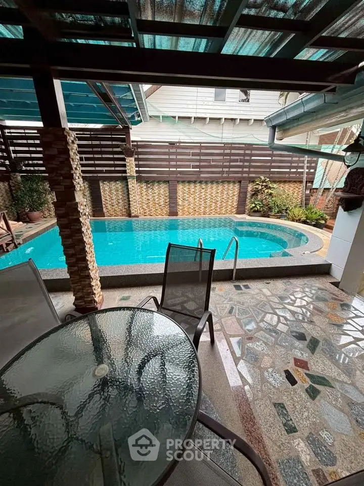Charming outdoor pool area with seating and unique stone flooring, perfect for relaxation and entertainment.