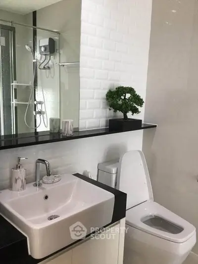 Modern bathroom with sleek fixtures and elegant white tiles, featuring a stylish sink and toilet.