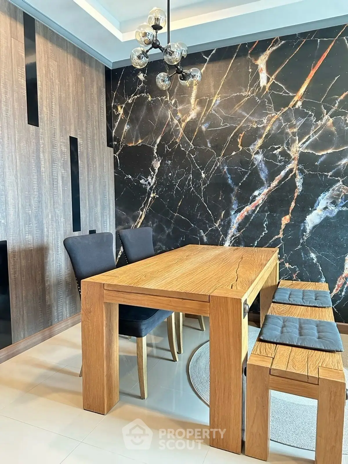 Stylish dining area with modern wooden table and elegant marble accent wall.