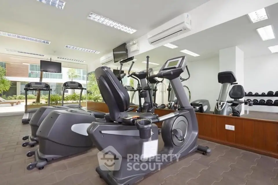 Modern gym with state-of-the-art equipment and mirrored walls in a luxury residential building.