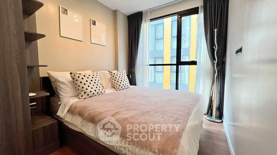 Modern bedroom with stylish decor and large window in urban apartment.