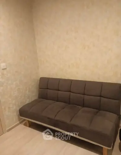 Cozy small living room with a modern brown sofa and neutral wall tones.