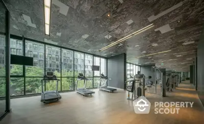 Modern gym with large windows and state-of-the-art equipment in luxury residential building.