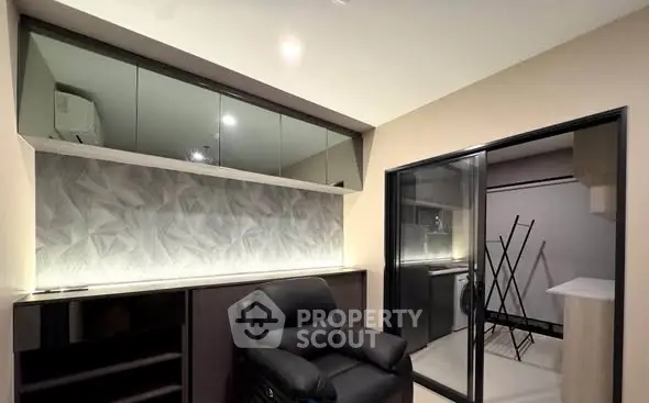 Modern living room with sleek storage and sliding glass doors leading to laundry area.