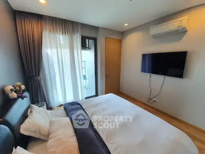 Modern bedroom with balcony access and wall-mounted TV in a stylish apartment.