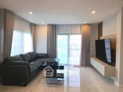 Spacious modern living room with sleek furniture and large TV, perfect for relaxation and entertainment.