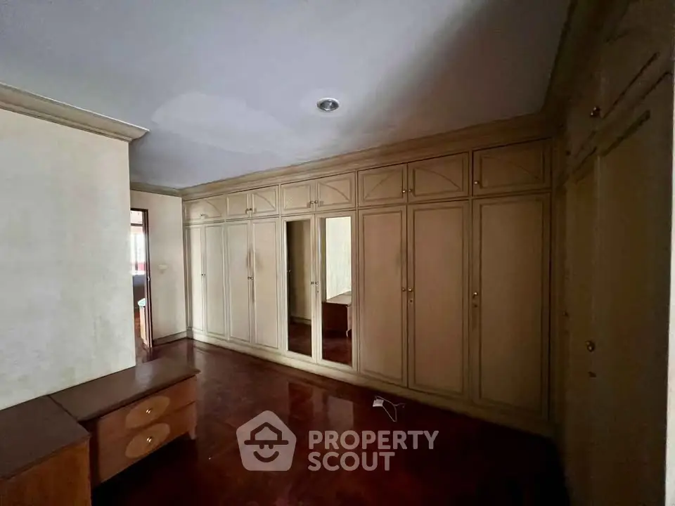 Spacious bedroom with elegant built-in wardrobes and polished wooden flooring.