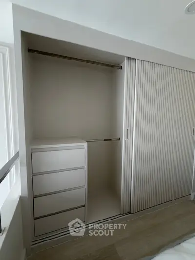Spacious modern closet with sliding doors and built-in drawers in a bright room.