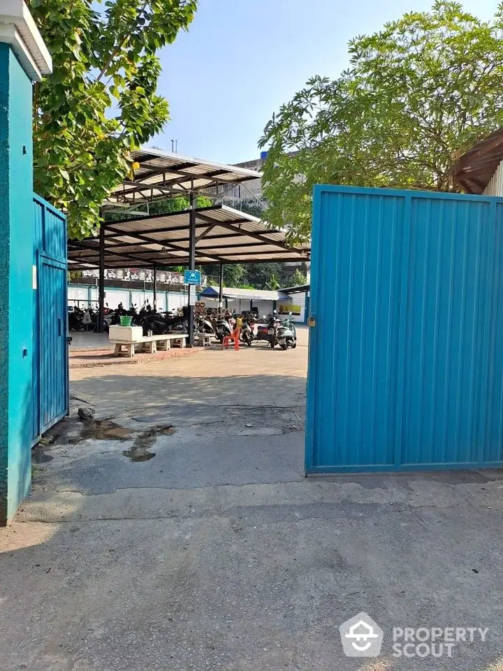 Spacious parking area with blue gate and covered motorcycle parking.