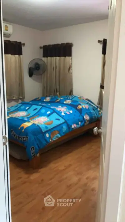 Cozy bedroom with wooden flooring and colorful bedding, perfect for a restful retreat.